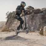 long range high speed 45mph scooter going off road jumping small hill in sandy desert environment