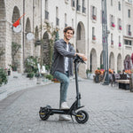 48V 1600W Dual Motor 32Miles Range 25MPH Electric Scooter in a beautiful city scene with stone walls and flowers